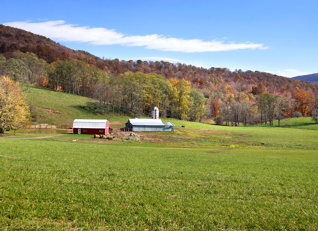 Oak Hill, WV - Scenic View of Colorful Trees Along the Mountains During the Fall Behind a Small Farm with Green Pasture in Oak Hill West Virginia