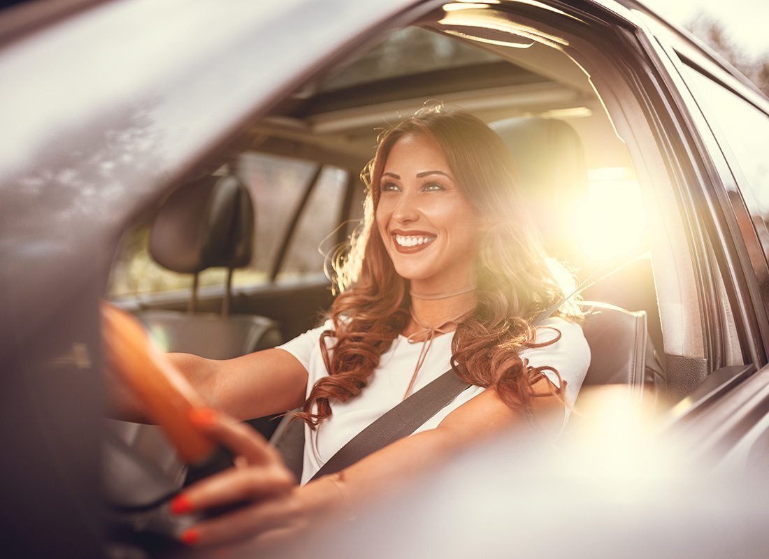 Service Center - Portrait of a Smiling Young Woman Wearing Business Clothing Driving her Car at Sunset